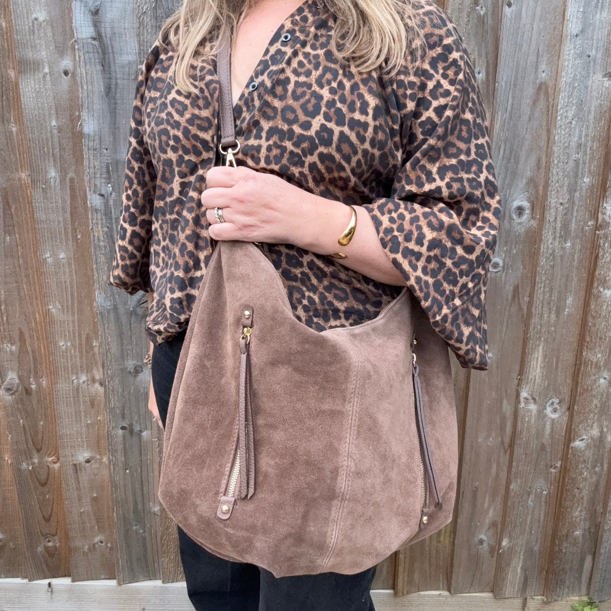 Person wearing a leopard print top holding a taupe suede crossbody shoulder bag  for autumn