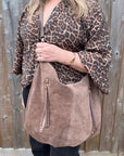 Person wearing a leopard print top holding a taupe suede crossbody shoulder bag  for autumn