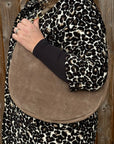 Woman wearing a leopard print coat with a taupe suede shoulder bag