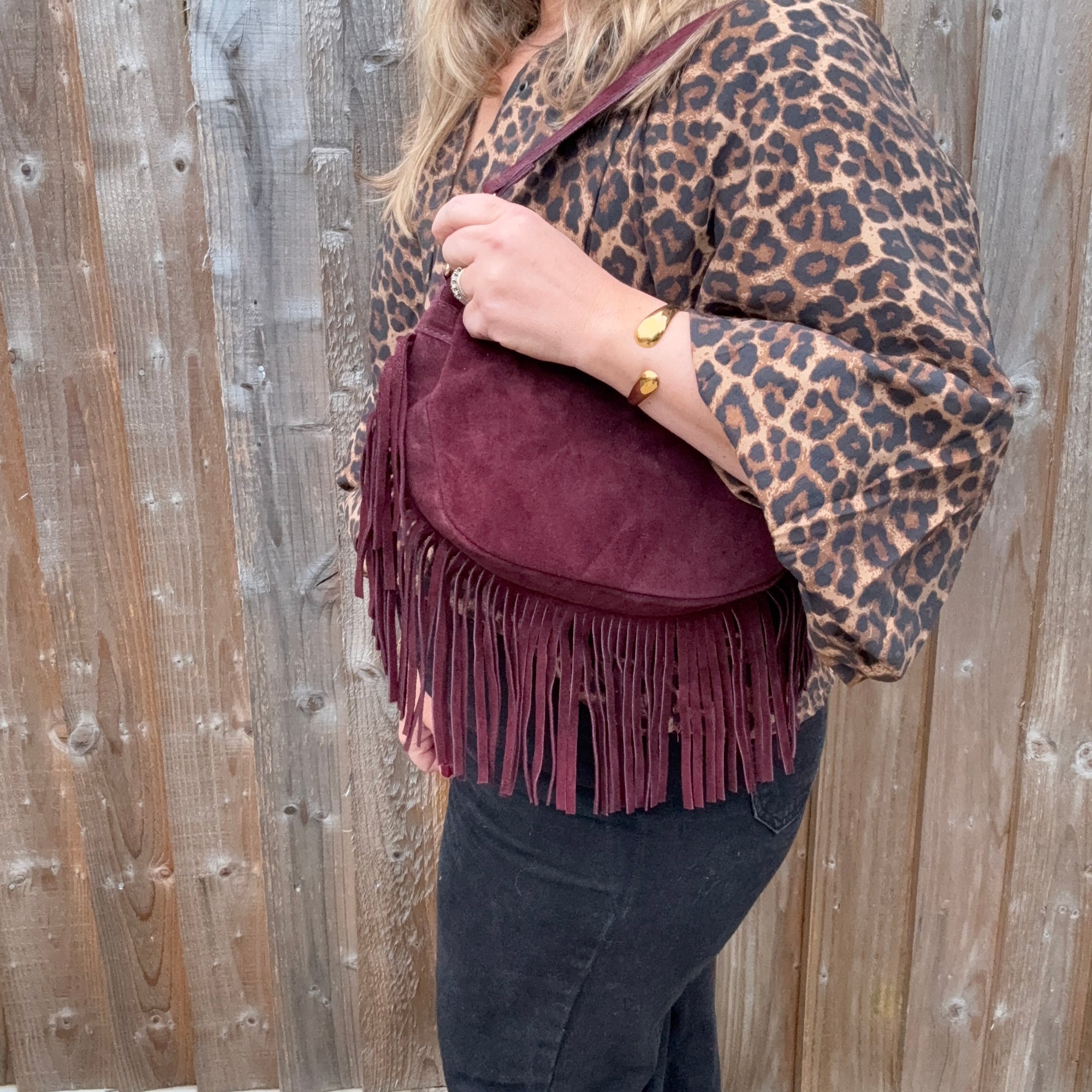 Person wearing a leopard print top & burgundy suede fringed shoulder bag for autumn winter