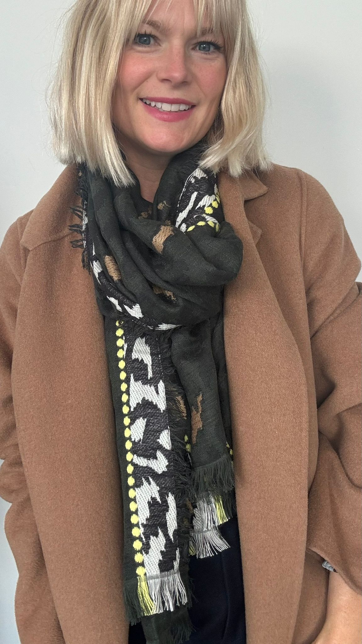Woman wearing a brown coat and a khaki patterned scarf for autumn winter