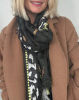 Woman wearing a brown coat and a khaki patterned scarf for autumn winter
