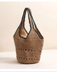 Woven beige and black raffia handbag with black trim on a light background.