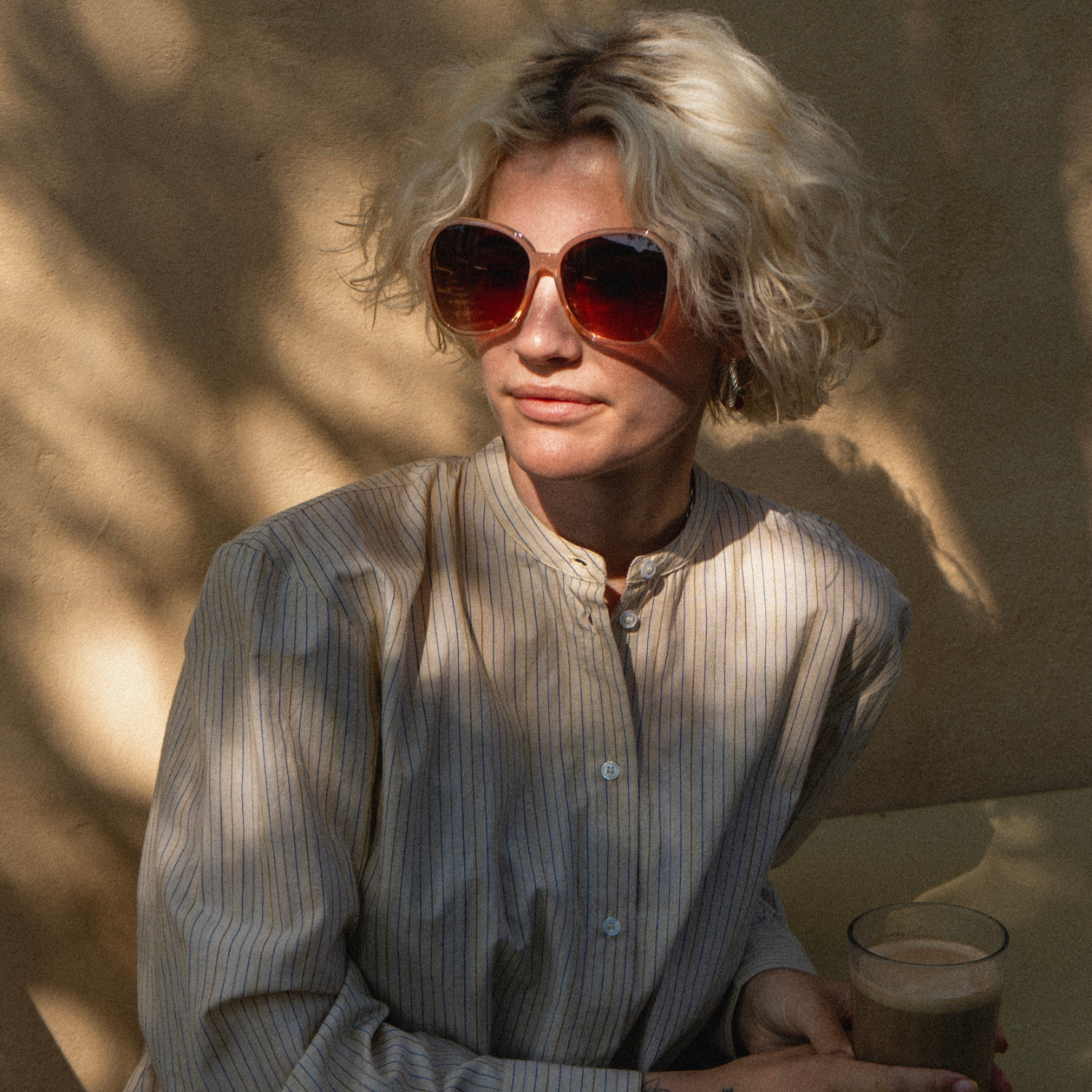 Woman wearing sunglasses and a light-colored shirt.