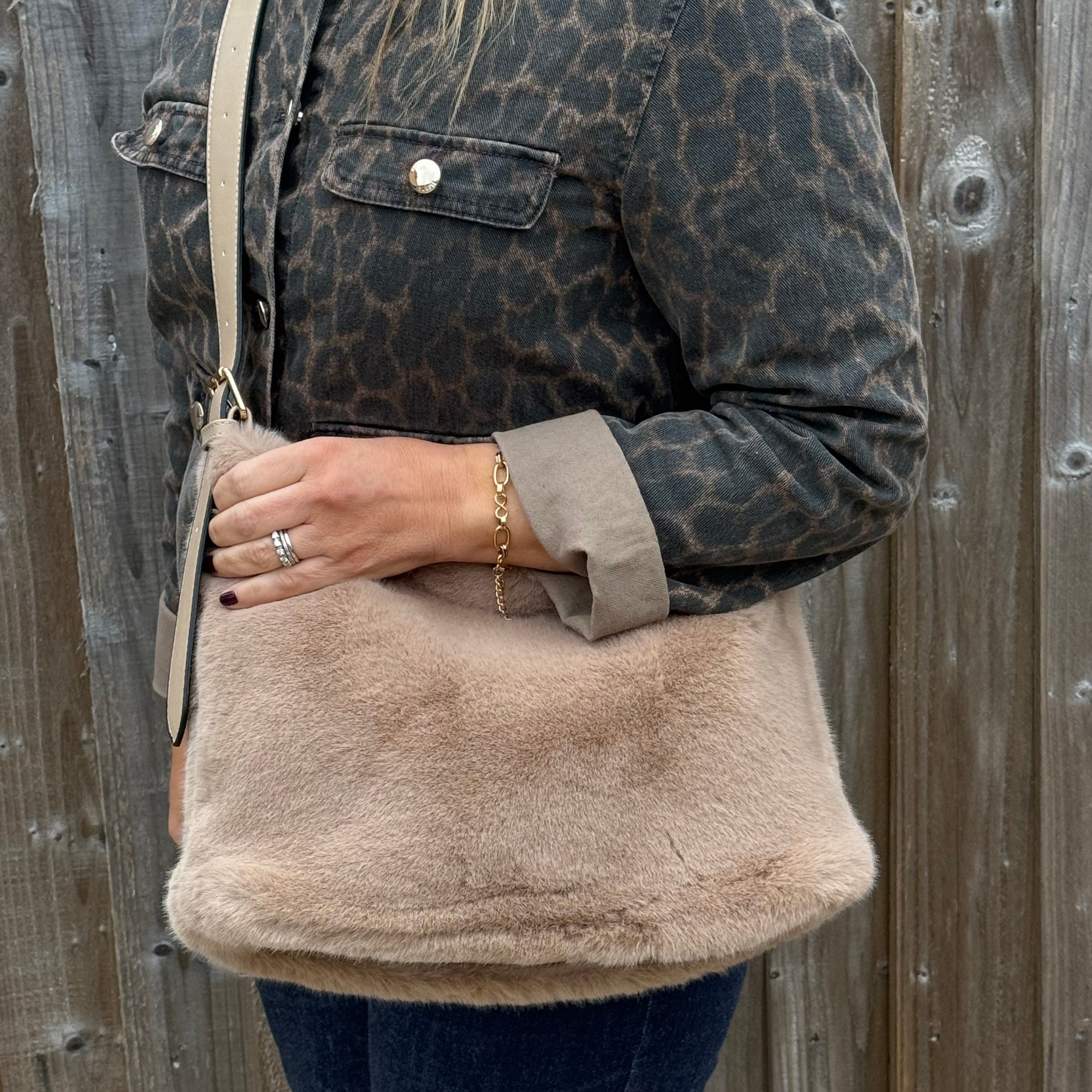 woman holding a beige shoulder bag with a leopard print jacket 