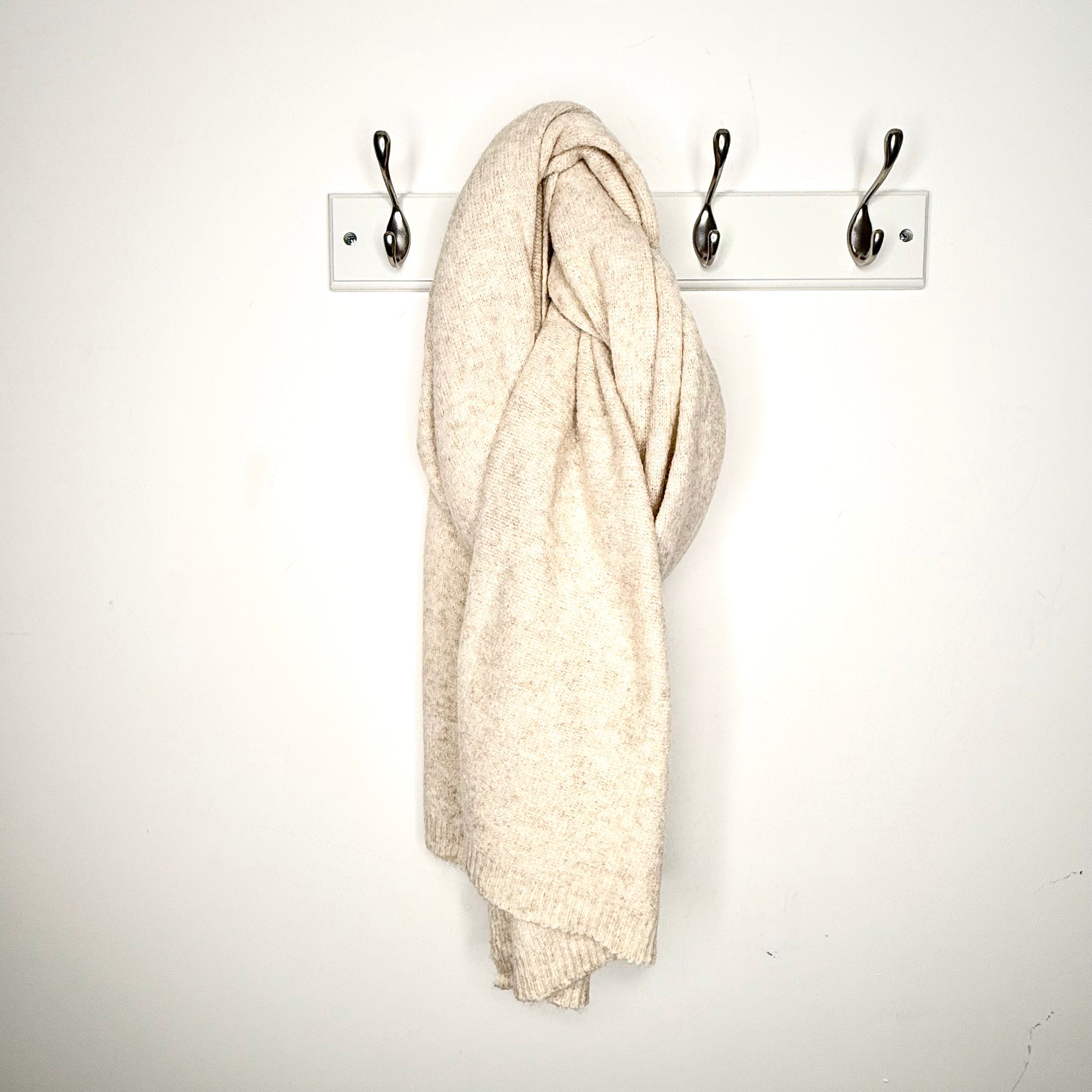 beige blanket scarf hanging of a peg. 