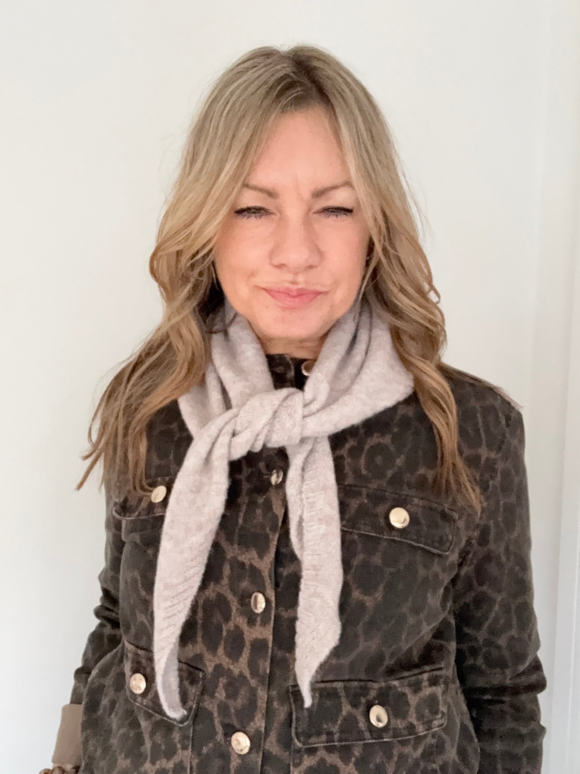 woman wearing a leopard print jacket with a beige triangle scarf