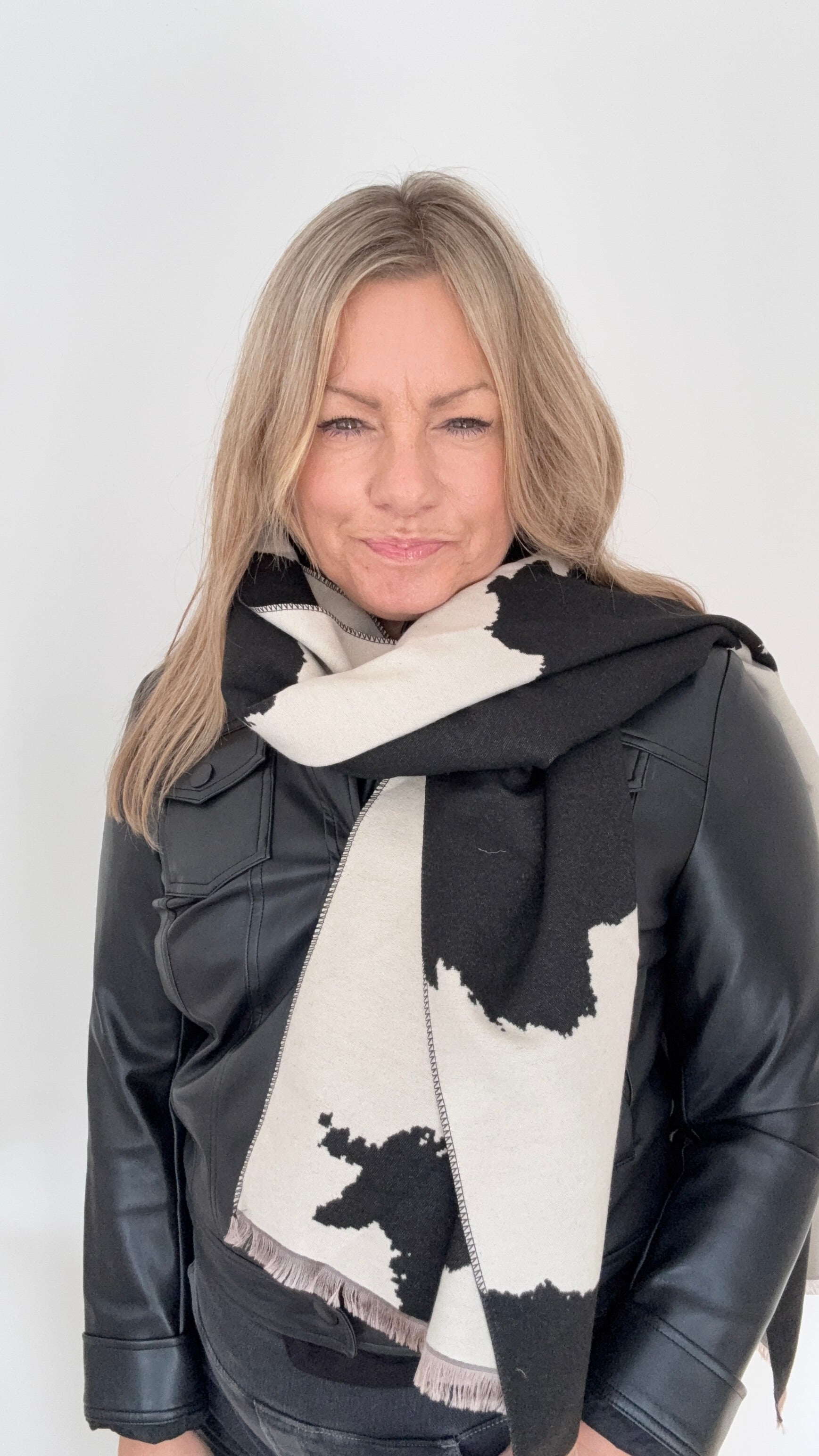 Woman wearing a black and white cow print patterned blanket scarf for Autumn Winter layering
