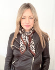 Woman wearing a brown leather jacket with a leopard print scarf 