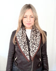 Woman wearing a brown leather jacket with a leopard print scarf 