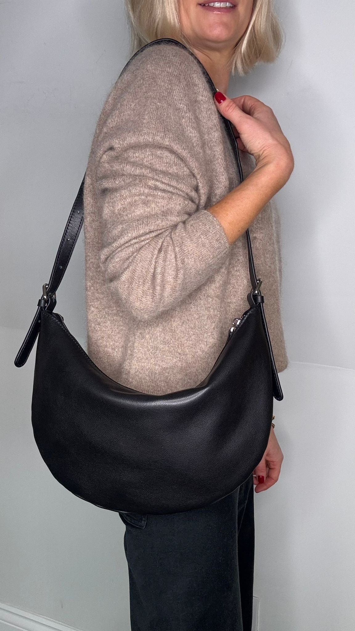 lady holding a black crossbody/ shoulder handbag. 