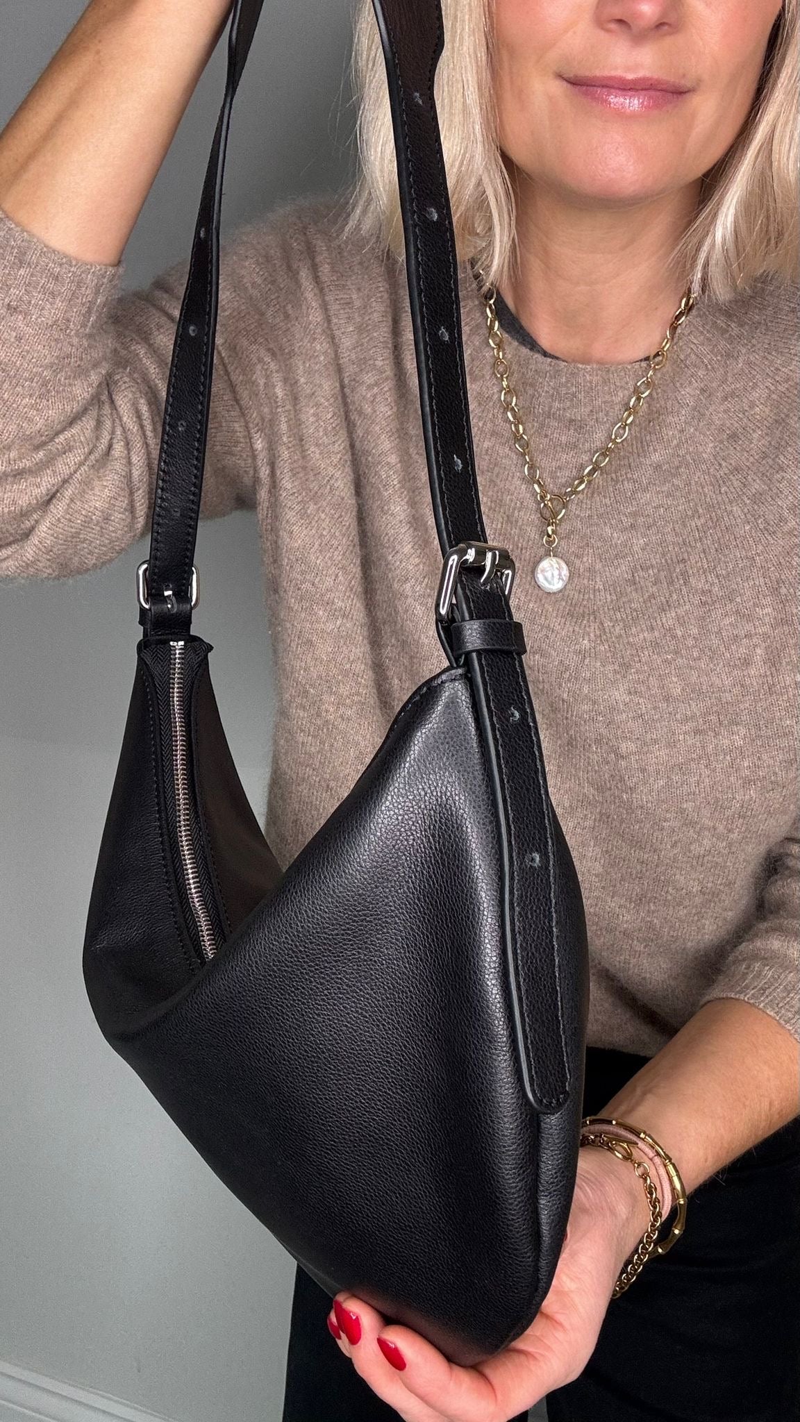 lady holding a black leather crossbody/ shoulder handbag. 