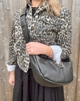 Woman wearing a leopard print jacket holding a black crossbody handbag.