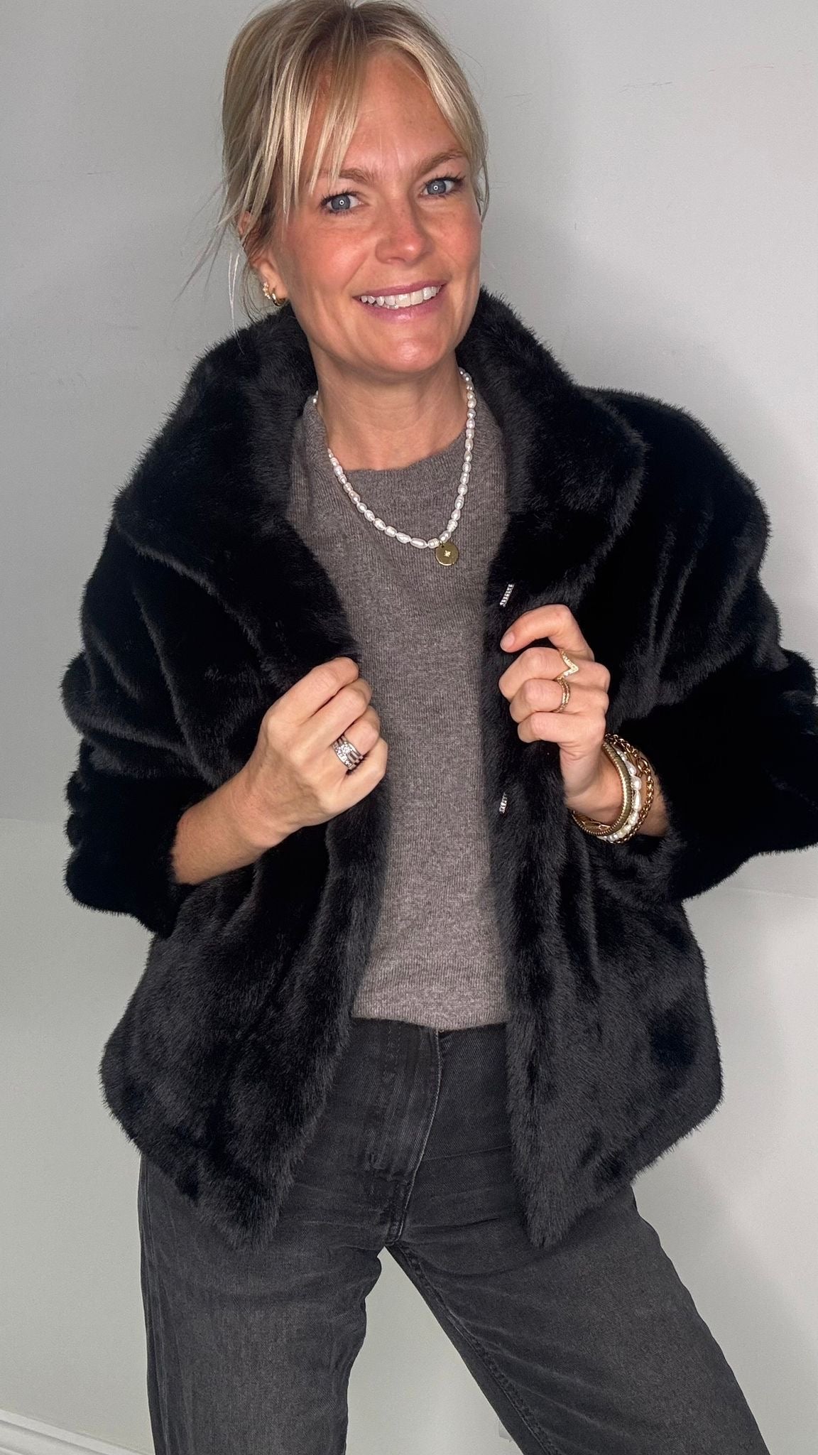 Woman wearing a black faux fur coat over a grey 