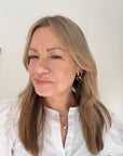 Woman wearing a white shirt with black flower earrings.