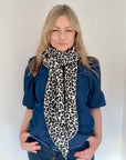 Woman wearing a black and white leopard print scarf and denim outfit 