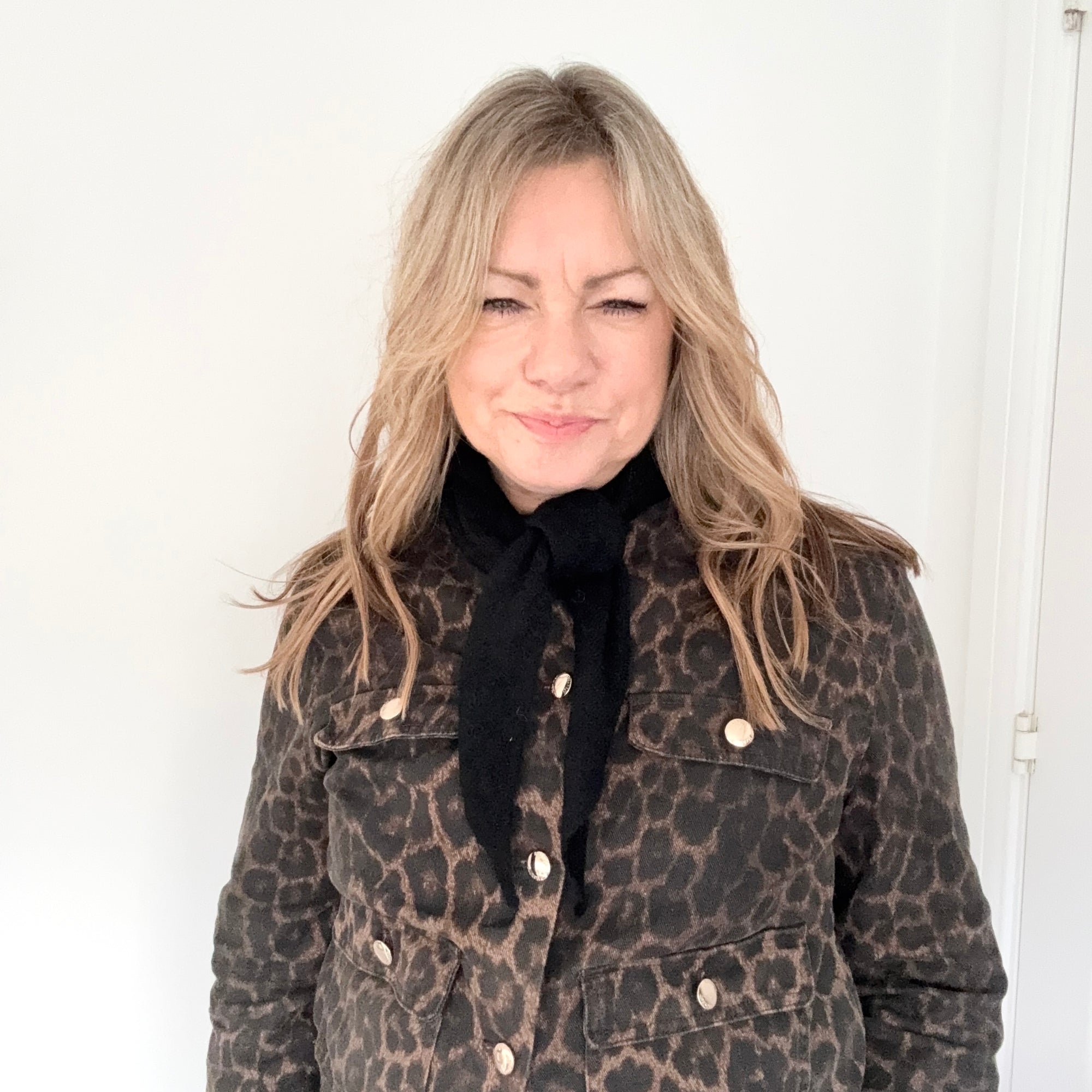 Woman wearing a leopard print coat with a black knitted triangle scarf. 