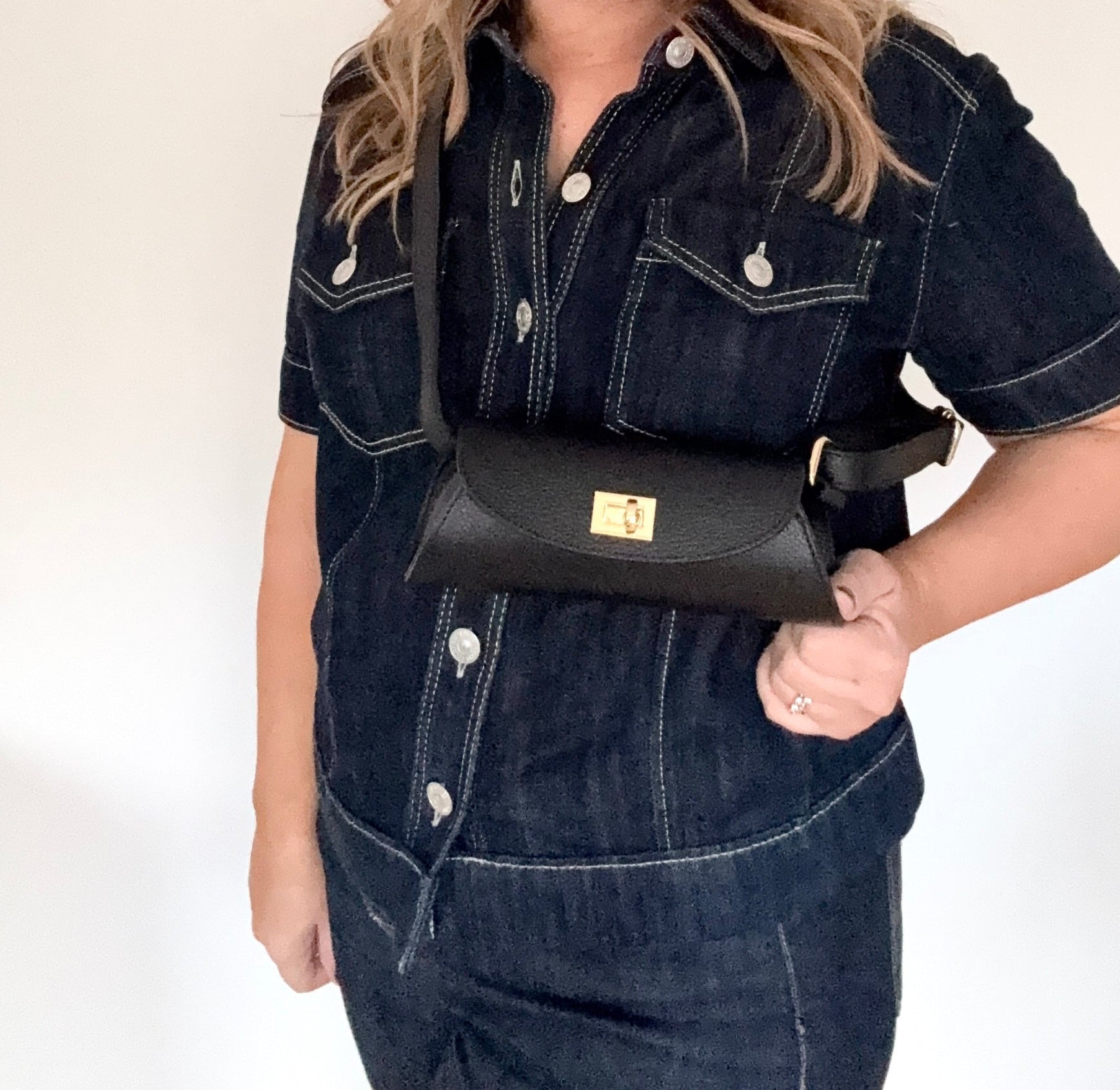 Woman holding a black leather buckle detail crossbody handbag 