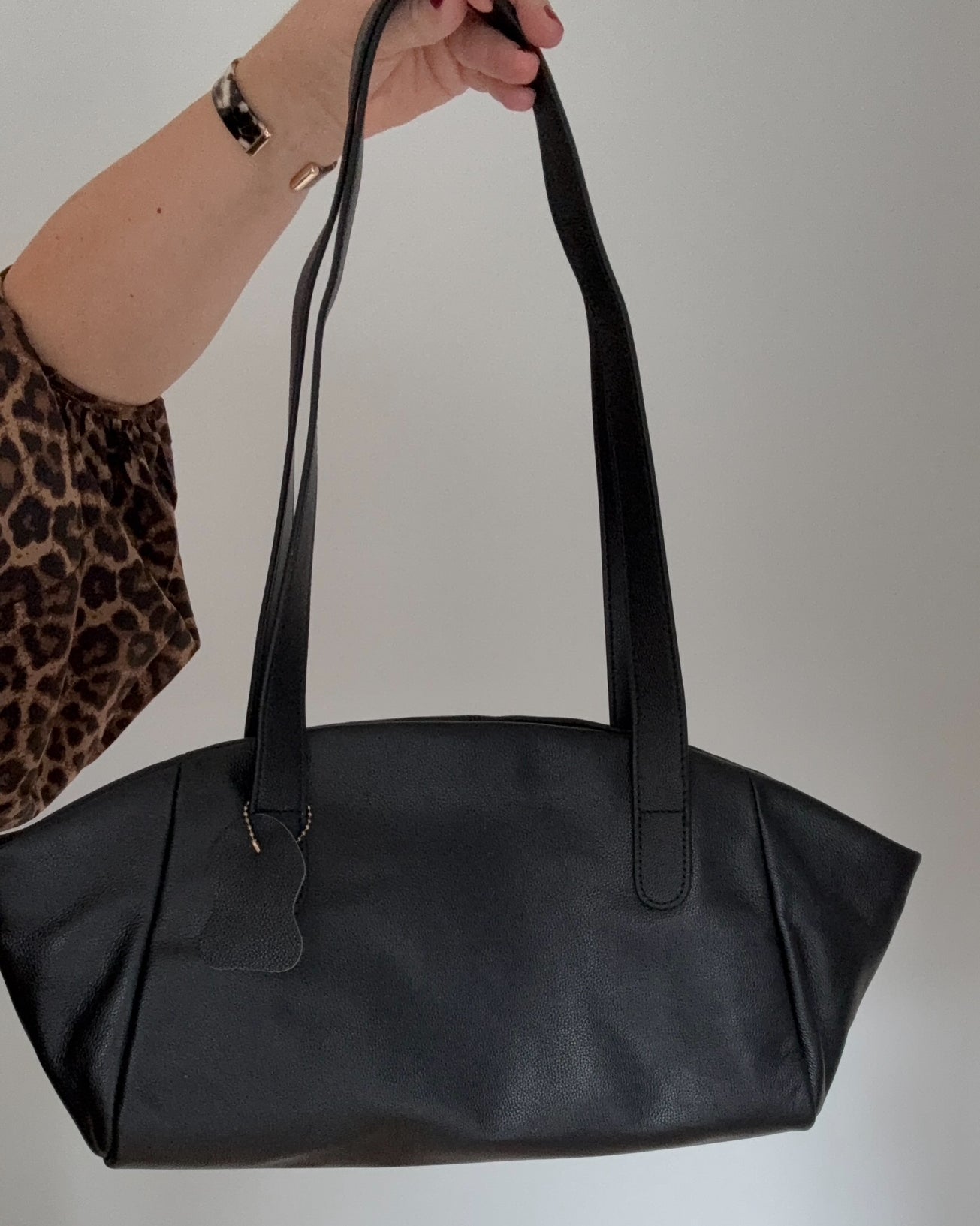 Black leather handbag held by a woman 