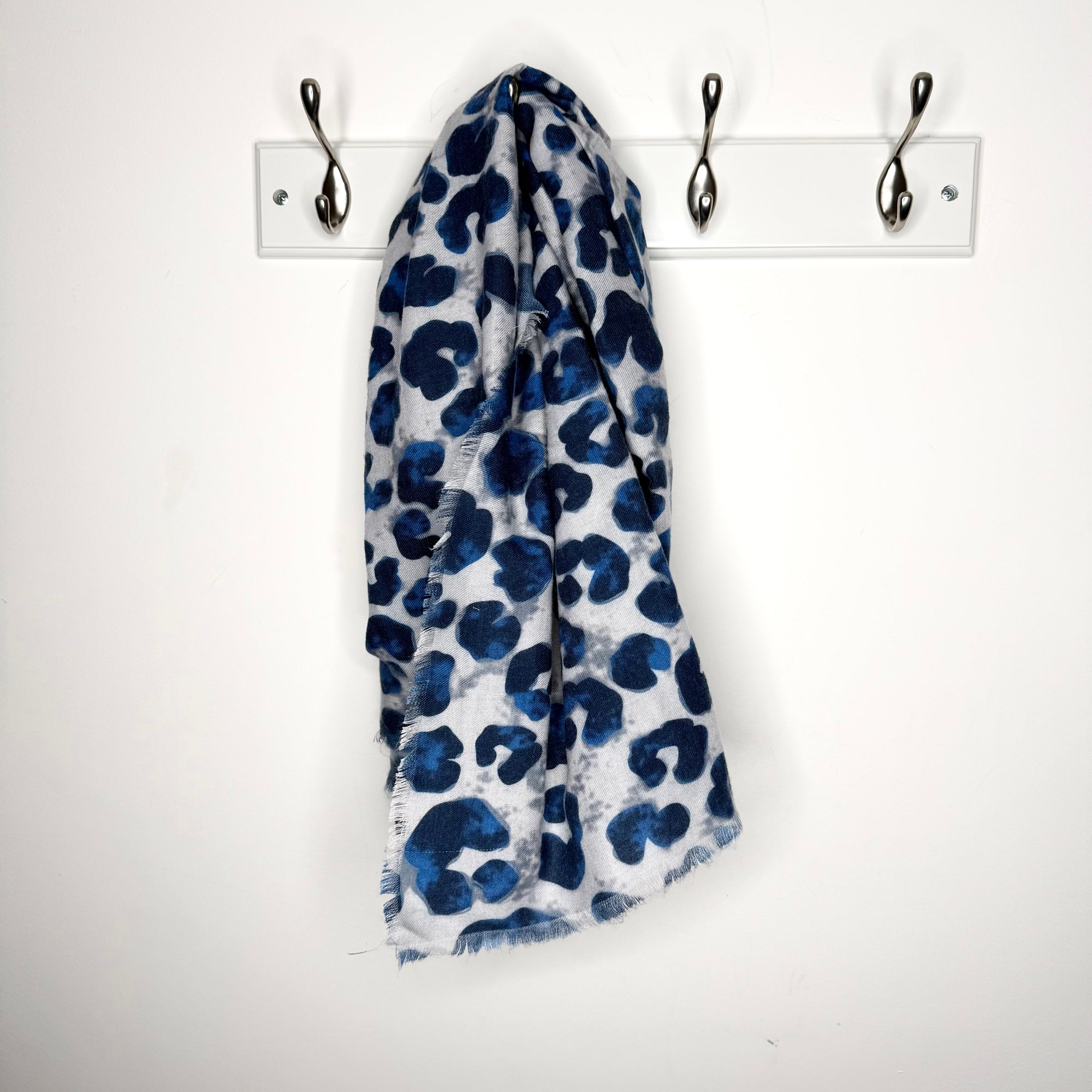Blue and white patterned scarf hanging on a rack against a white background