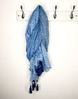 Blue and white striped scarf draped over a coat rack on a white wall.