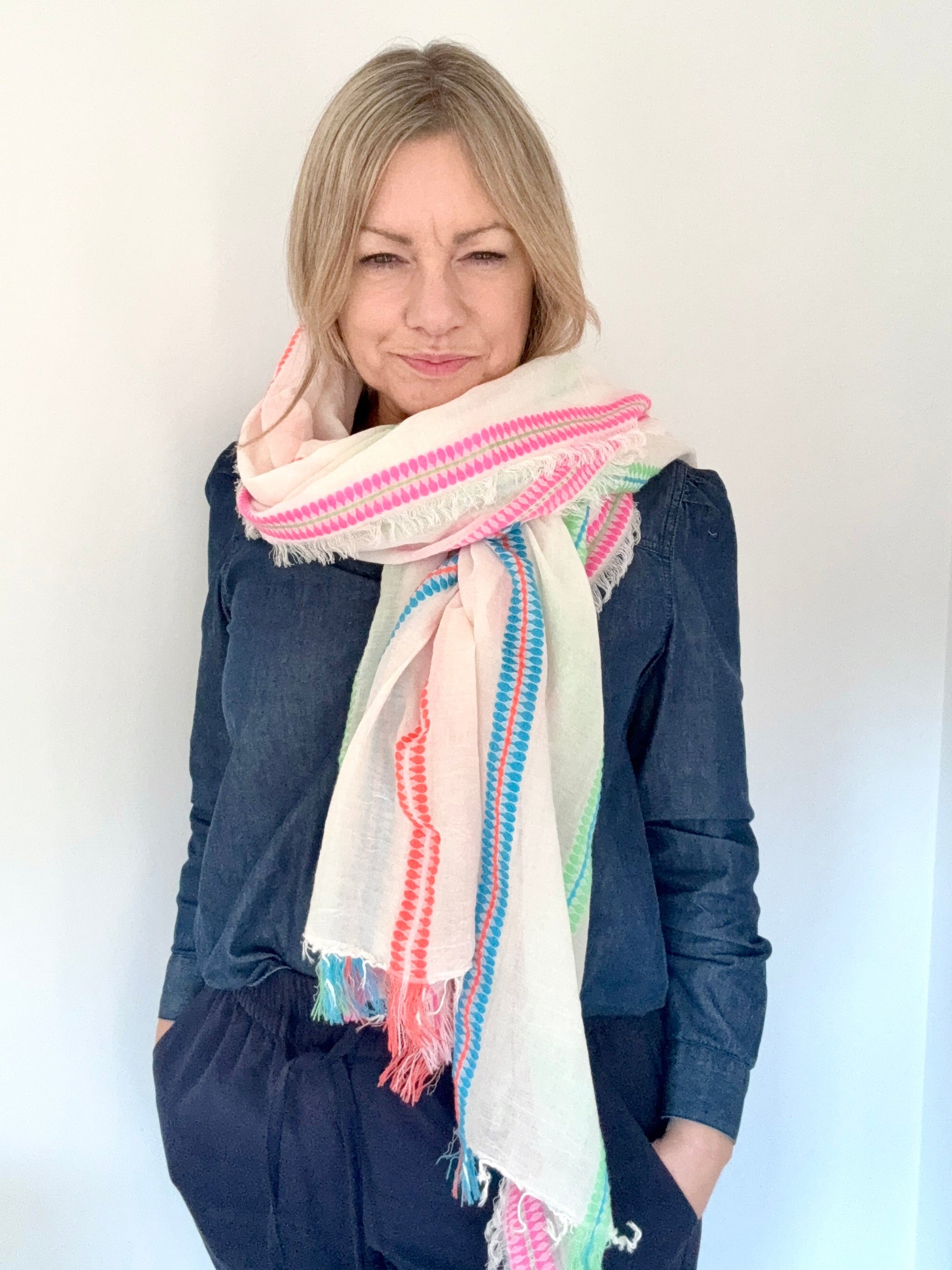 Woman wearing a colorful scarf  and denim shirt against a white background