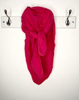 Pink scarf draped over a hook on a white wall