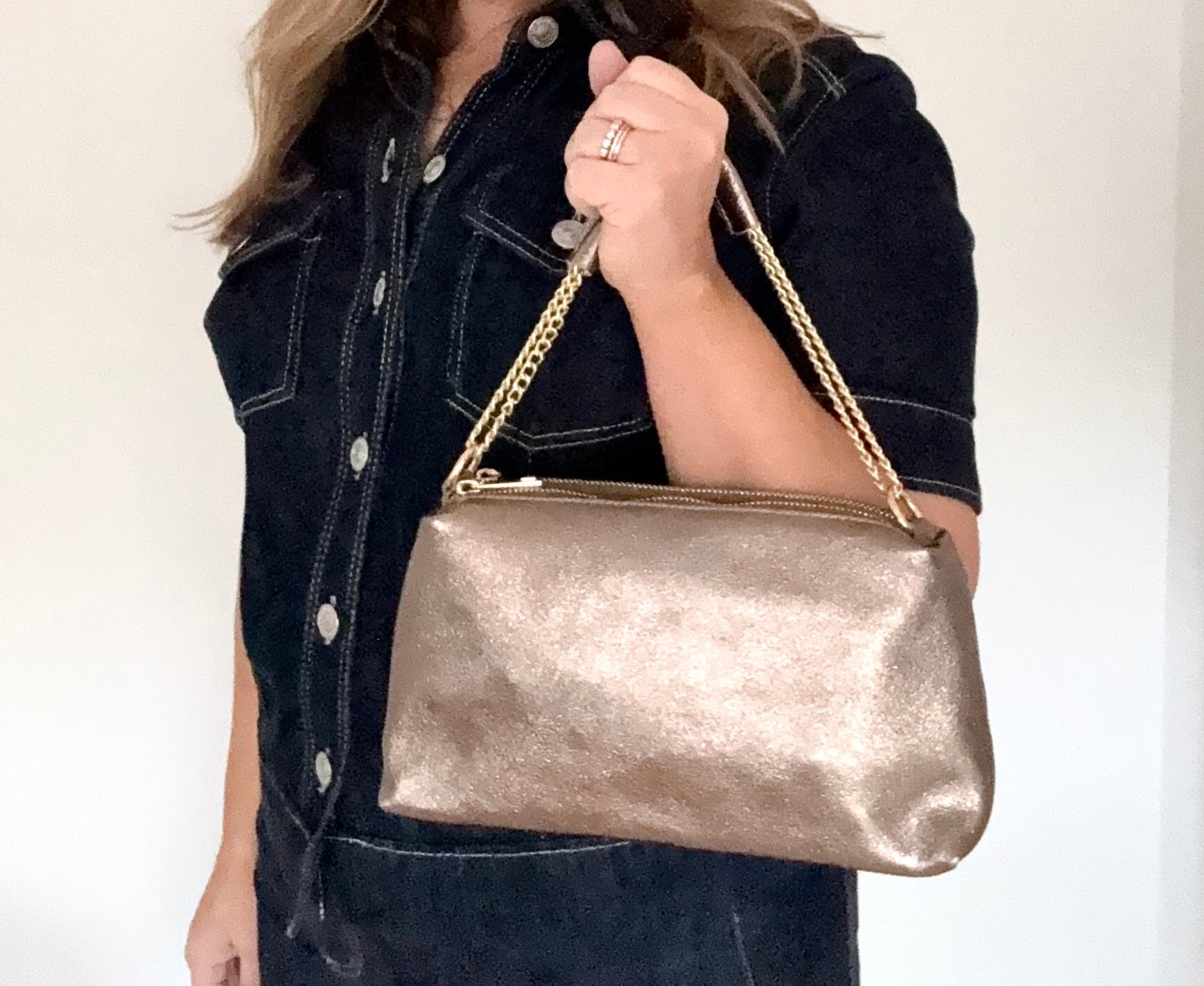 woman  holding a bronze leather clutch/ shoulder/ crossbody handbag with a bronze chain strap