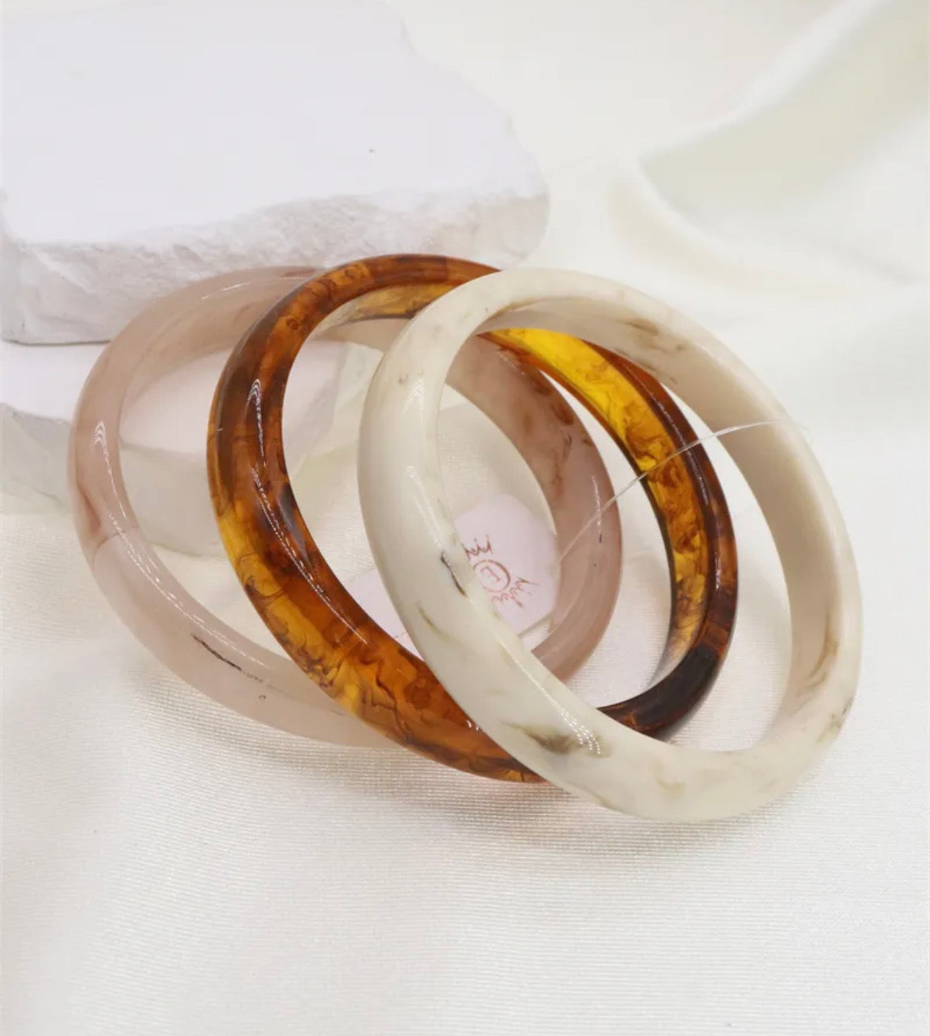 Three tortoiseshell bangles stacked on a white fabric background