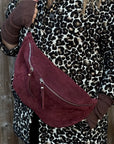 lady  wearing a leopard print coat with a burgundy suede large crossbody handbag 