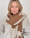 Woman wearing an Autumn Winter camel and cream cow print patterned blanket scarf for layering
