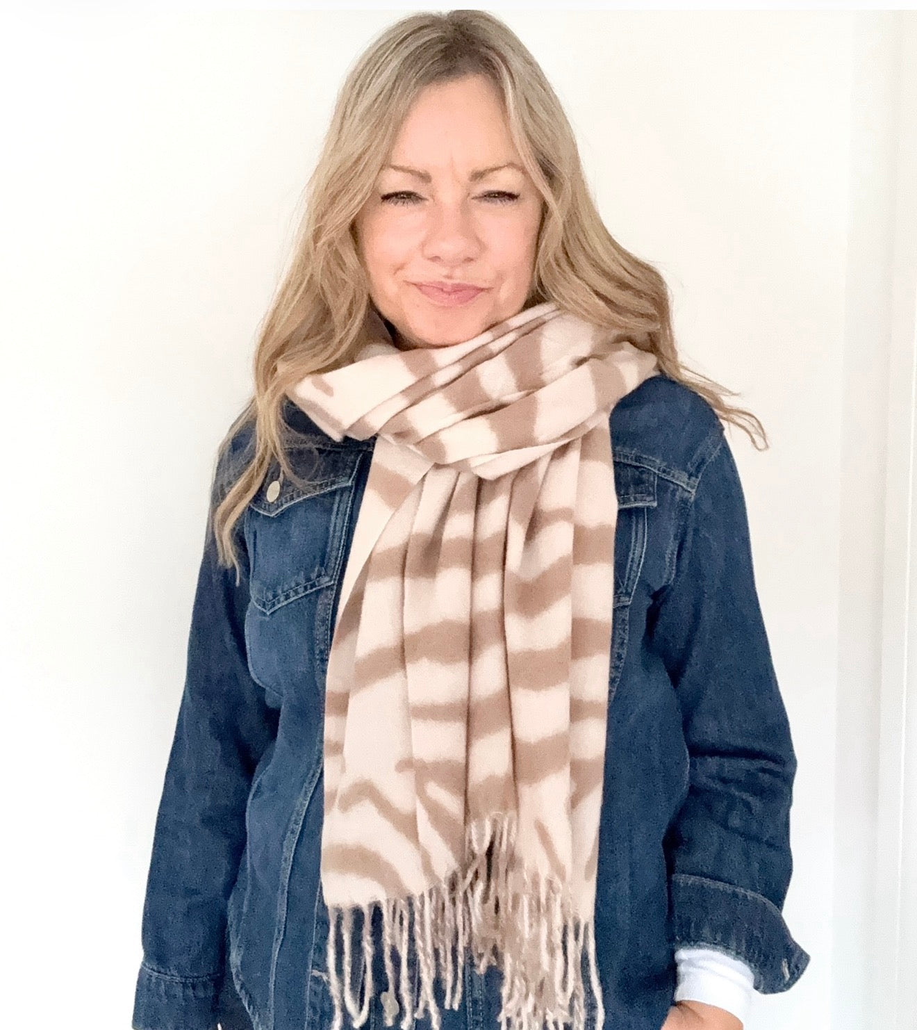 Woman wearing a cream and camel zebra print patterned scarf and denim jacket 