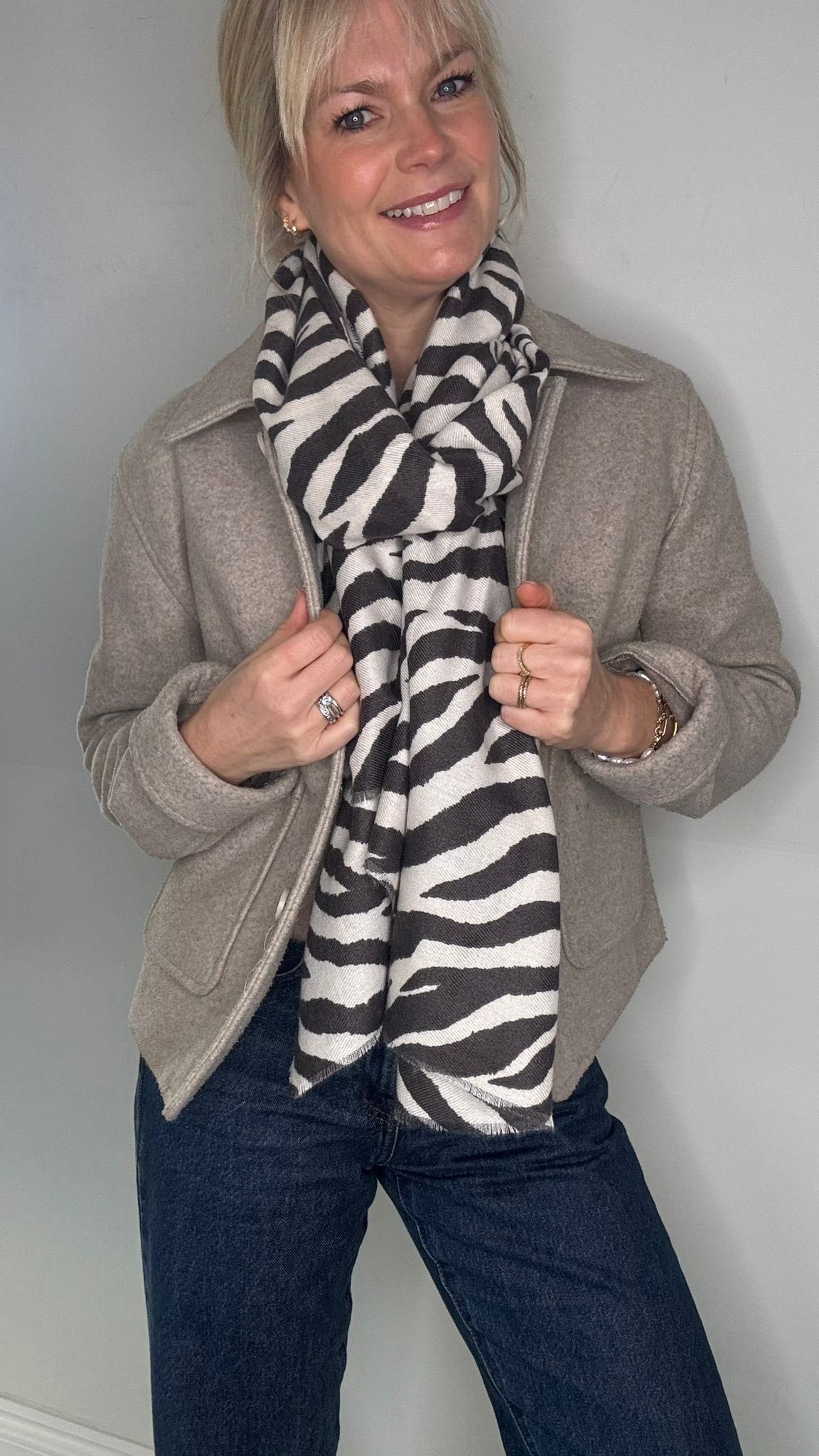 Woman wearing a charcoal and white zebra pattern scarf with a grey jacket