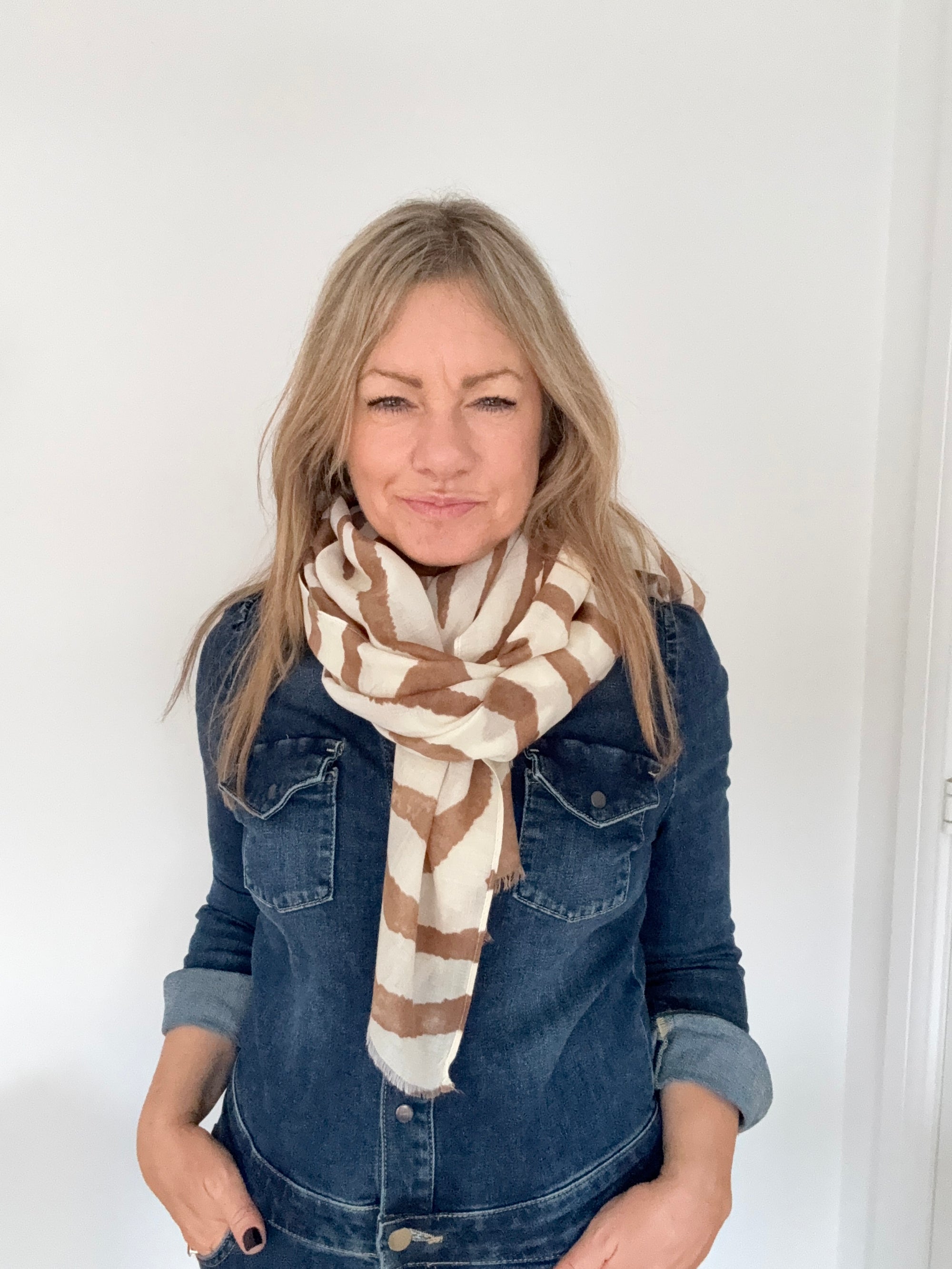 Woman wearing a denim jacket and a coffee and cream zebra print striped scarf 