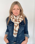 Woman wearing a denim jacket and a coffee and cream zebra print striped scarf 