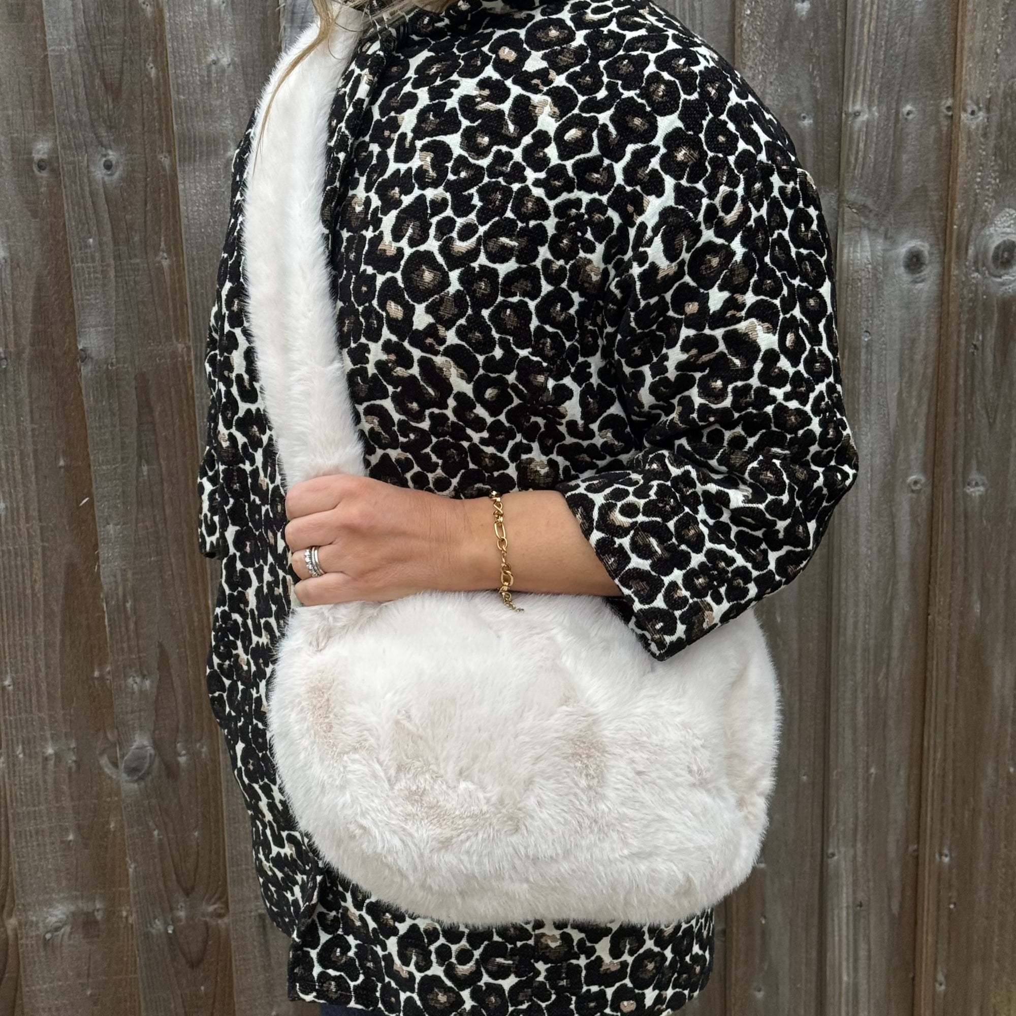 woman wearing a leopard print coat with white fur lining against a wooden background