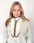Woman wearing a light-colored coat with a cream & taupe cotton triangle scarf 