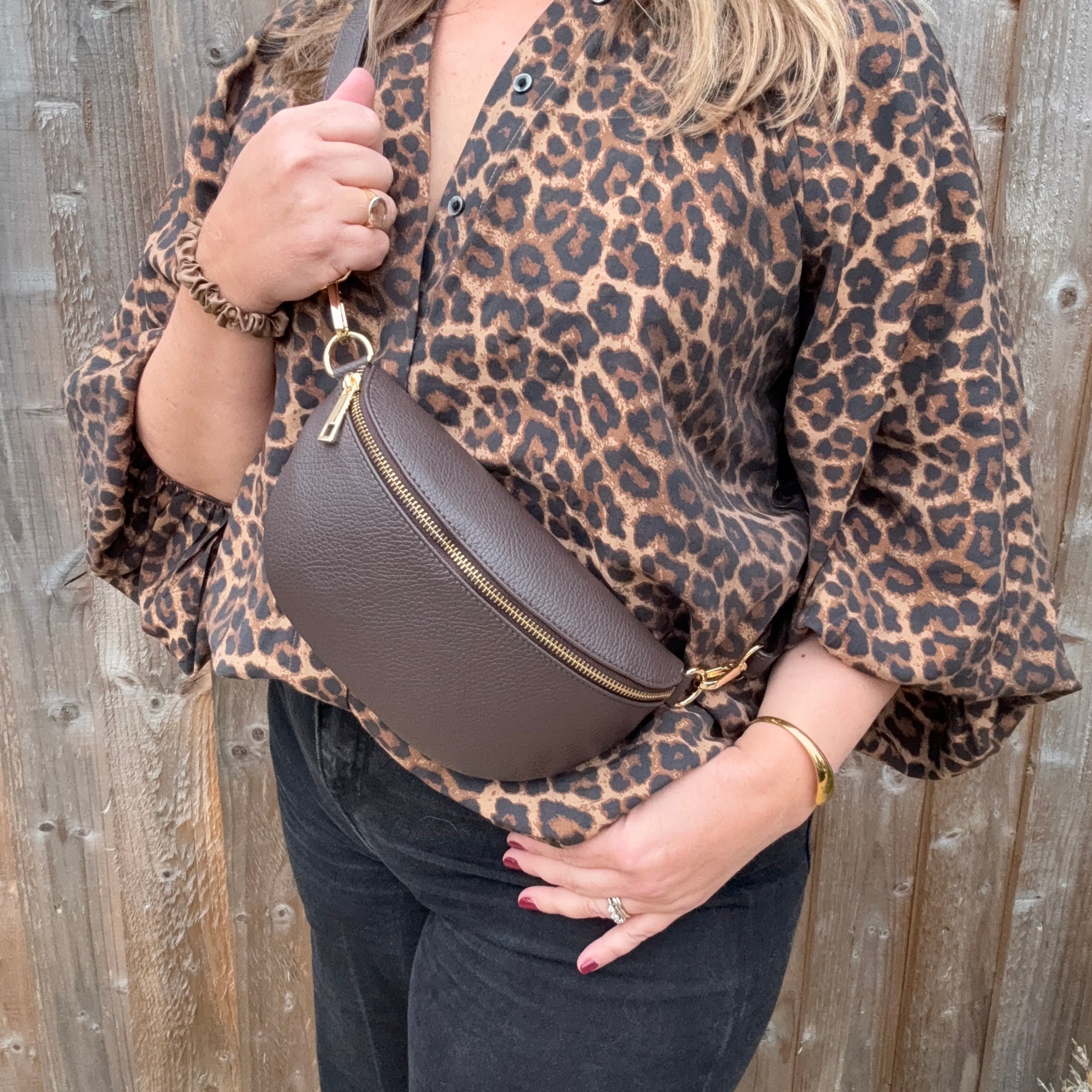 Woman wearing a leopard print shirt holding a brown leather crossbody for autumn winter