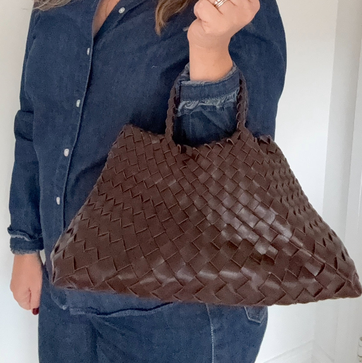 woman holding a brown woven handbag against a white background