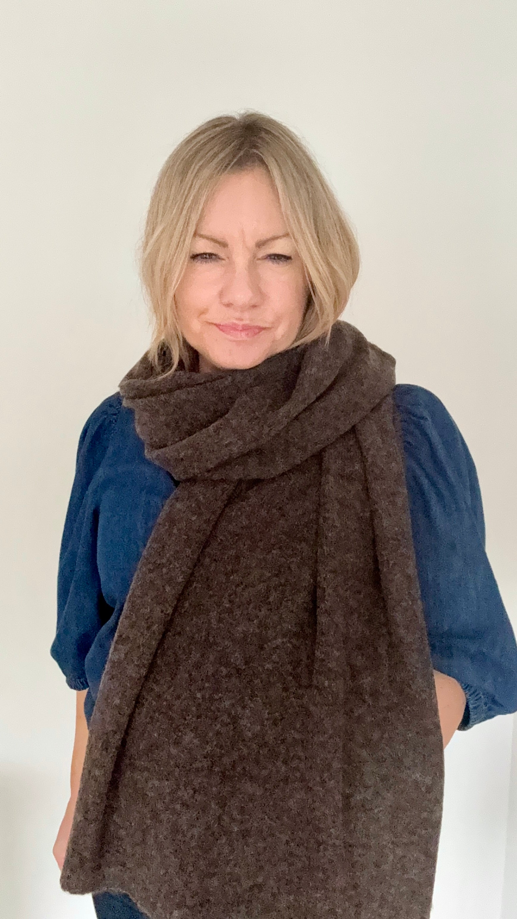 Woman wearing a brown knitted scarf over a blue denim top 