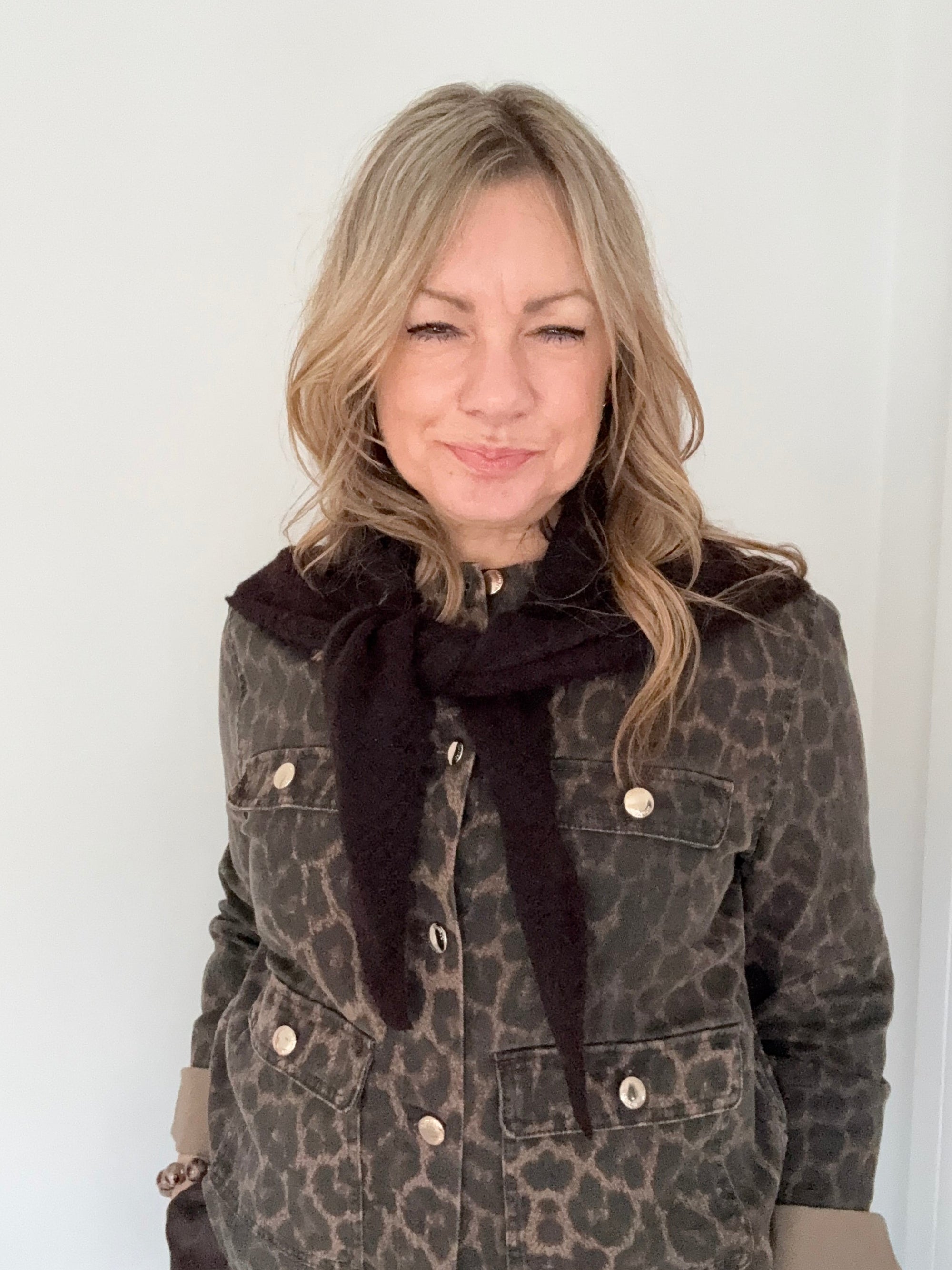 Person wearing a leopard print jacket with a dark brown triangle scarf 