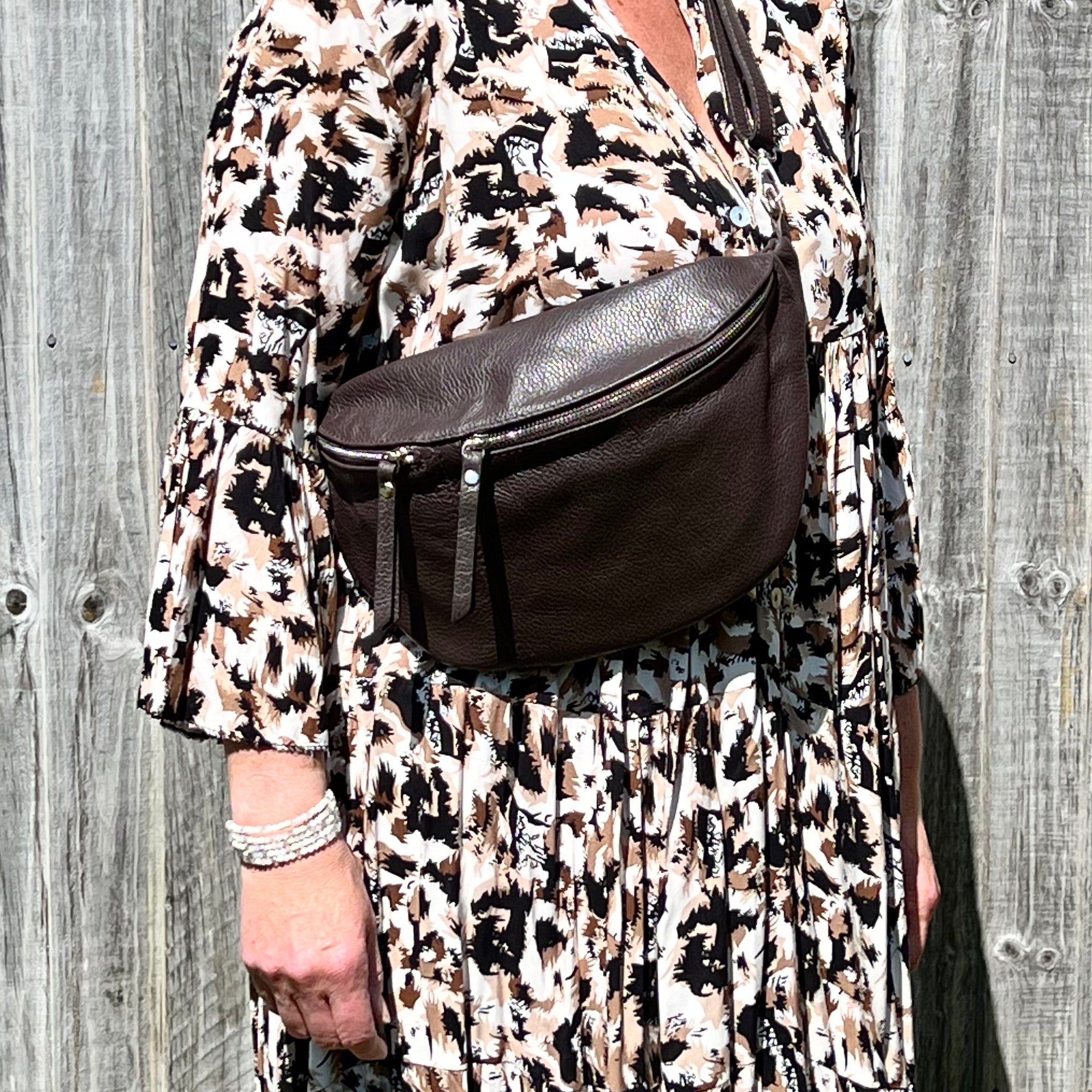 woman wearing a dark brown large crossbody bum bag with gold accented hardware. 