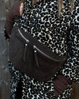 woman wearing a leopard print coat with a brown suede crossbody handbag 