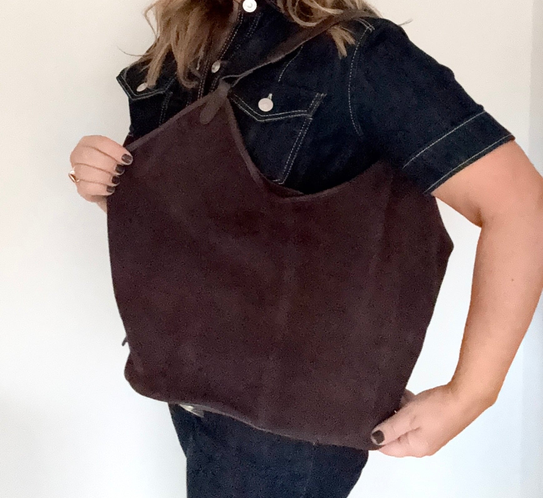 woman holding a dark  brown suede leather tote / shoulder bag 