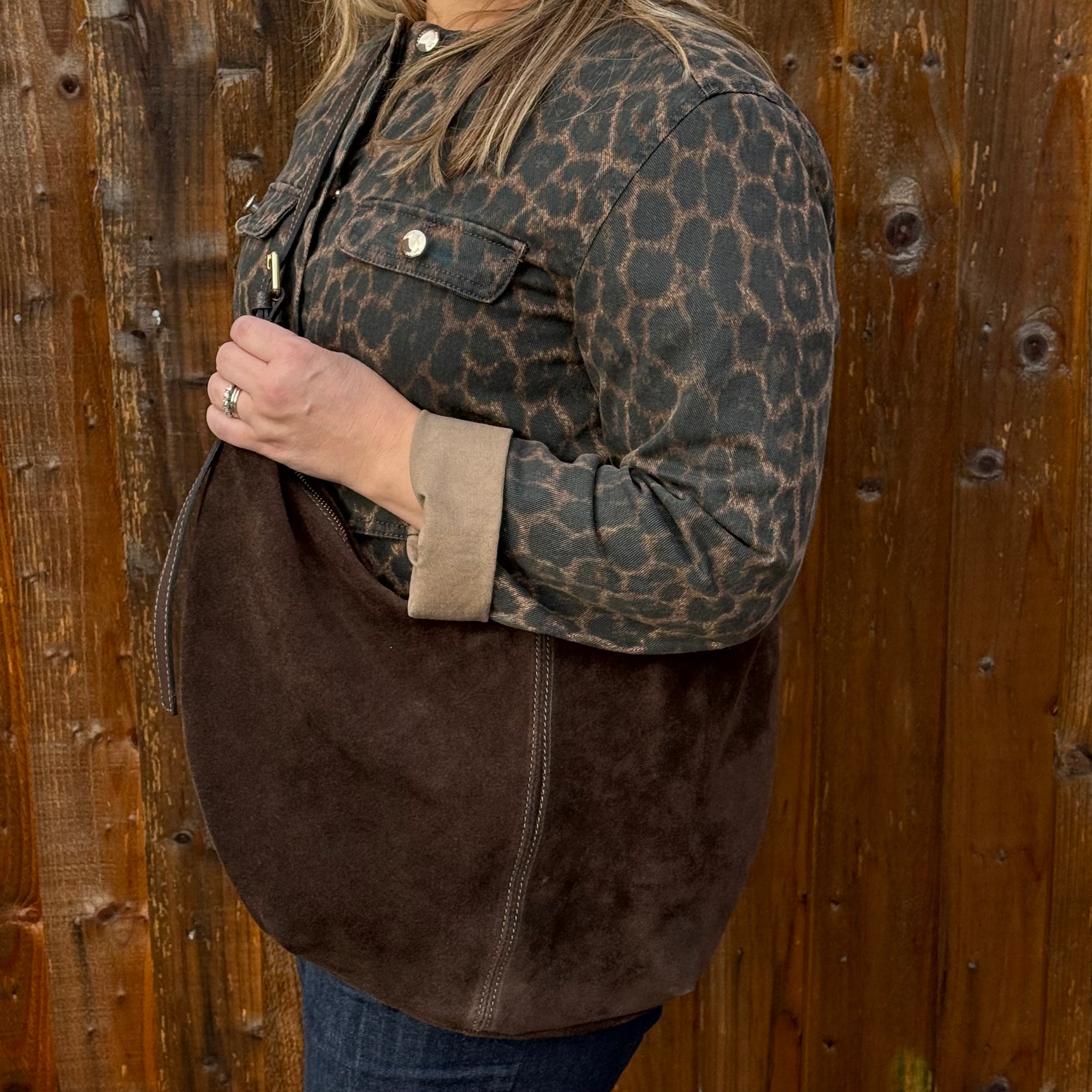 Woman holding a dark brown suede XL crossbody swing bag 
