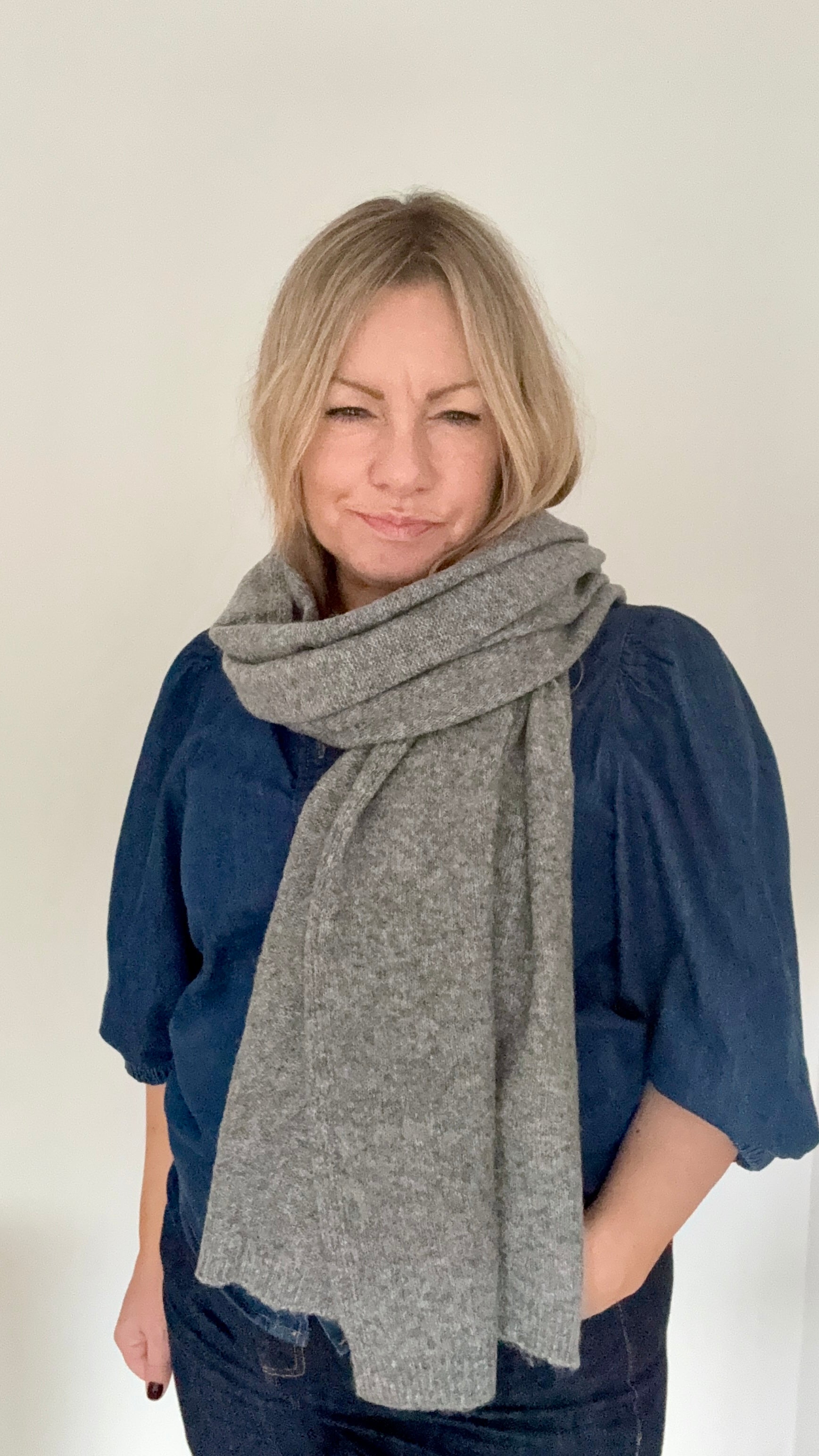 Woman wearing a grey knitted scarf and blue denim top