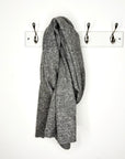 dark grey scarf draped over a peg against a white wall 