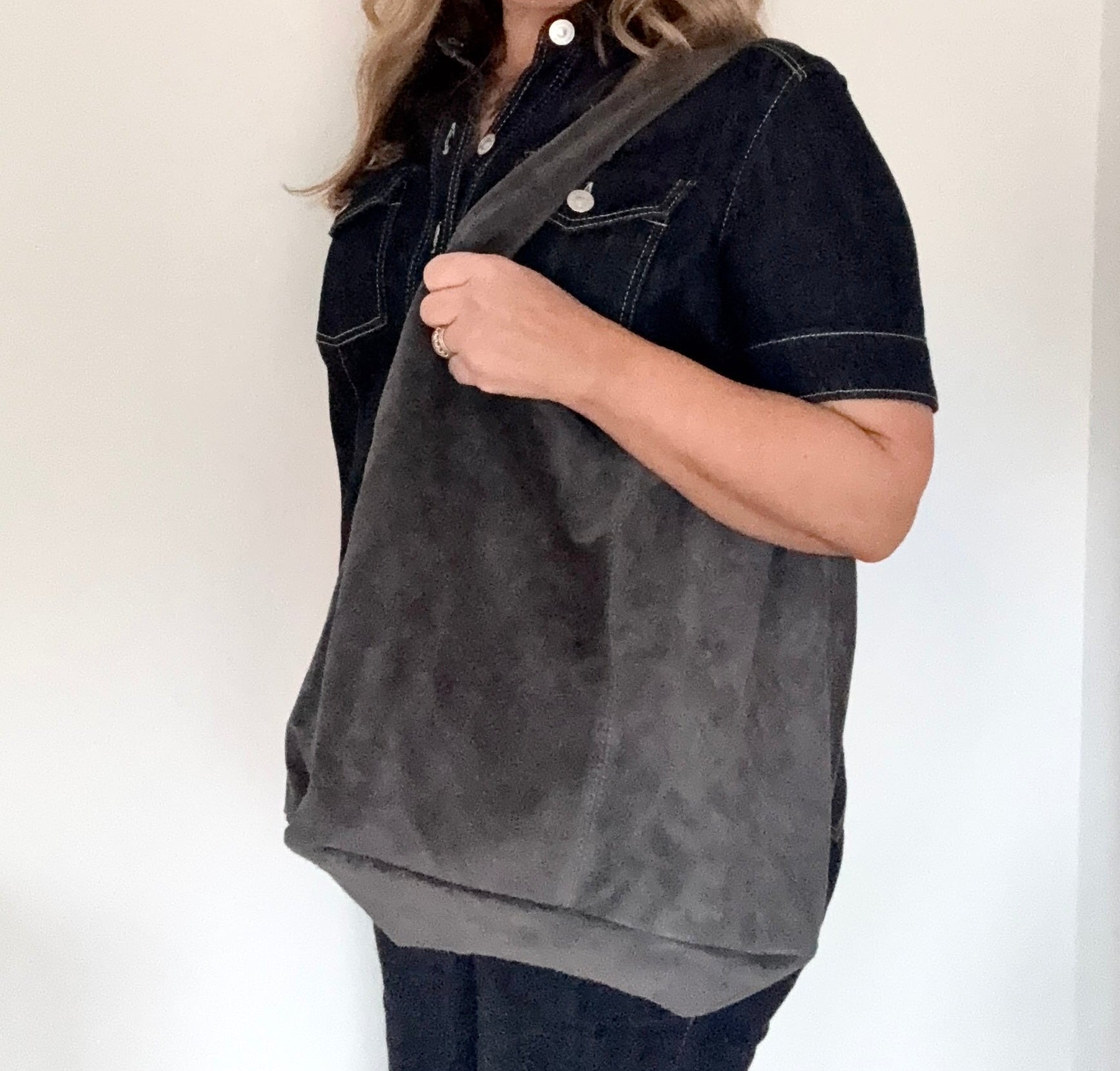 Woman holding a dark grey shoulder/ tote bag 