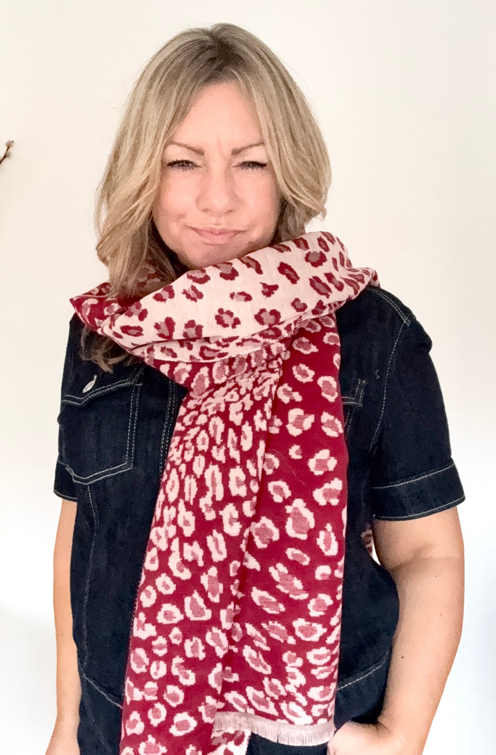 Woman wearing a red and white leopard print scarf with a denim jacket]