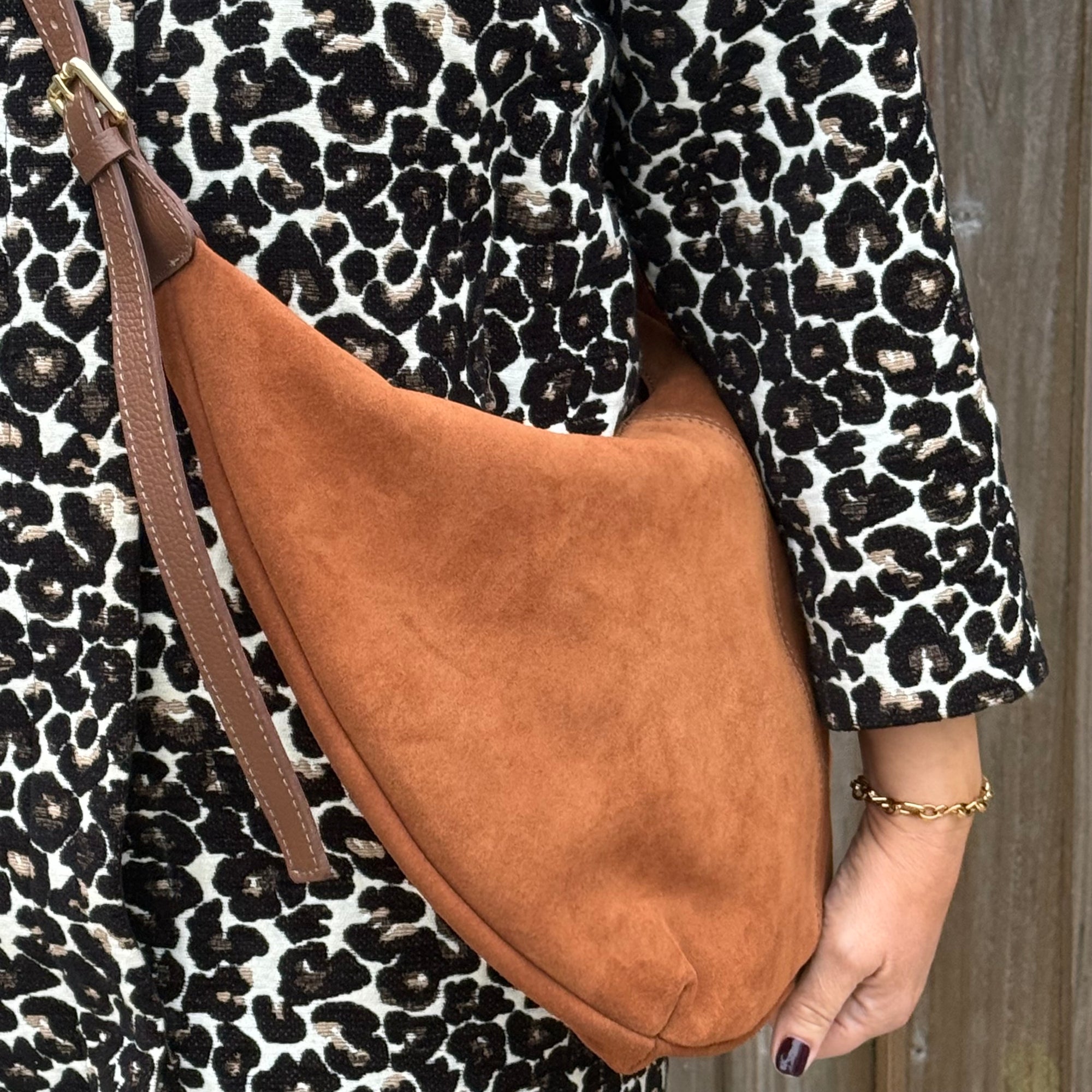dark tan XL crossbody bag held by a person wearing a leopard print coat.